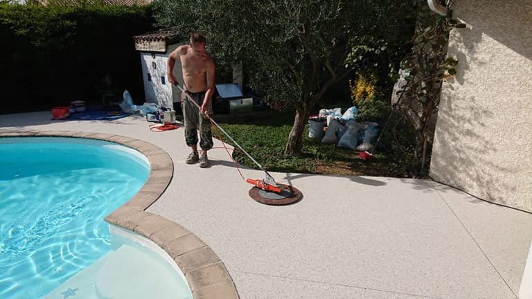 Réalisation d'une terrasse en résine moquette de pierre au bord d'une piscine à Escalquens.