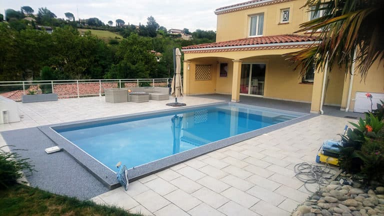 Réalisation d'une terrasse en résine moquette de pierre au bord d'une piscine à Blagnac.